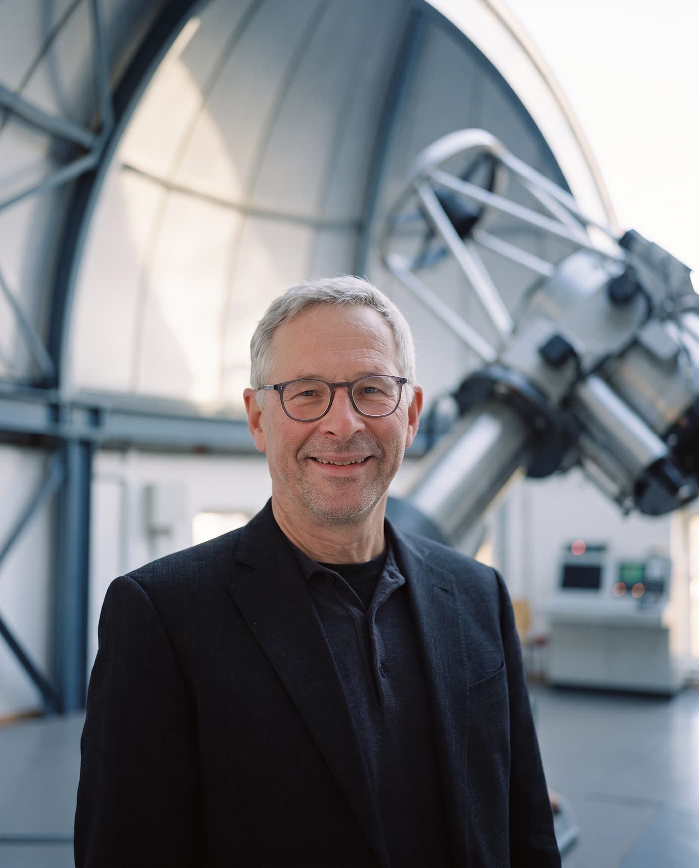 Andreas Burkert vor einem Teleskop in einer Sternwartenkuppel
